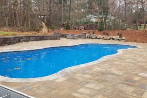 Swimming pool with decorative retaining wall and fire pit